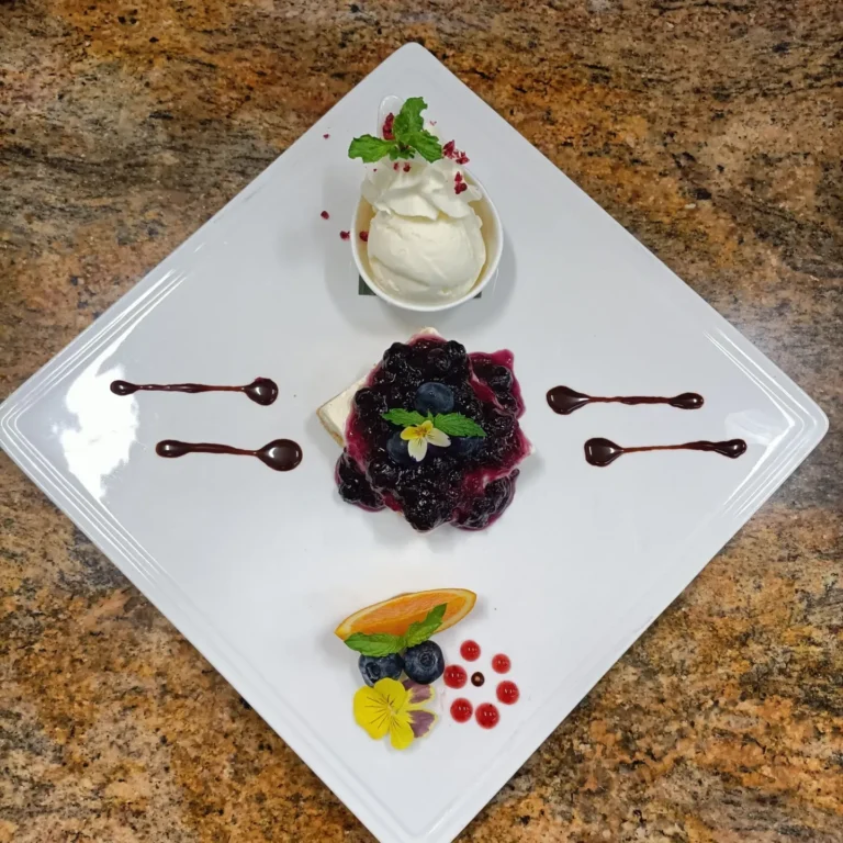 plated cheesecake dessert with berry compote and vanilla ice cream