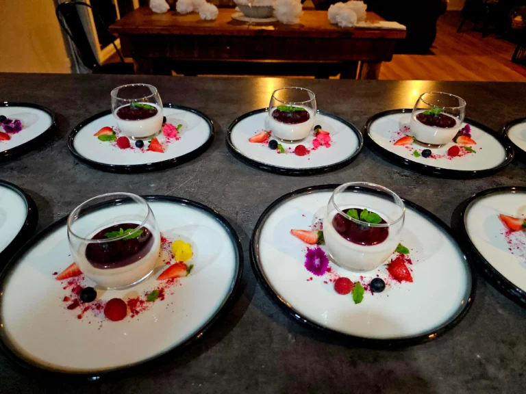 panna-cotta-dark-berry-compote-edible-flowers-black-rimmed-plates-private-chef-dessert